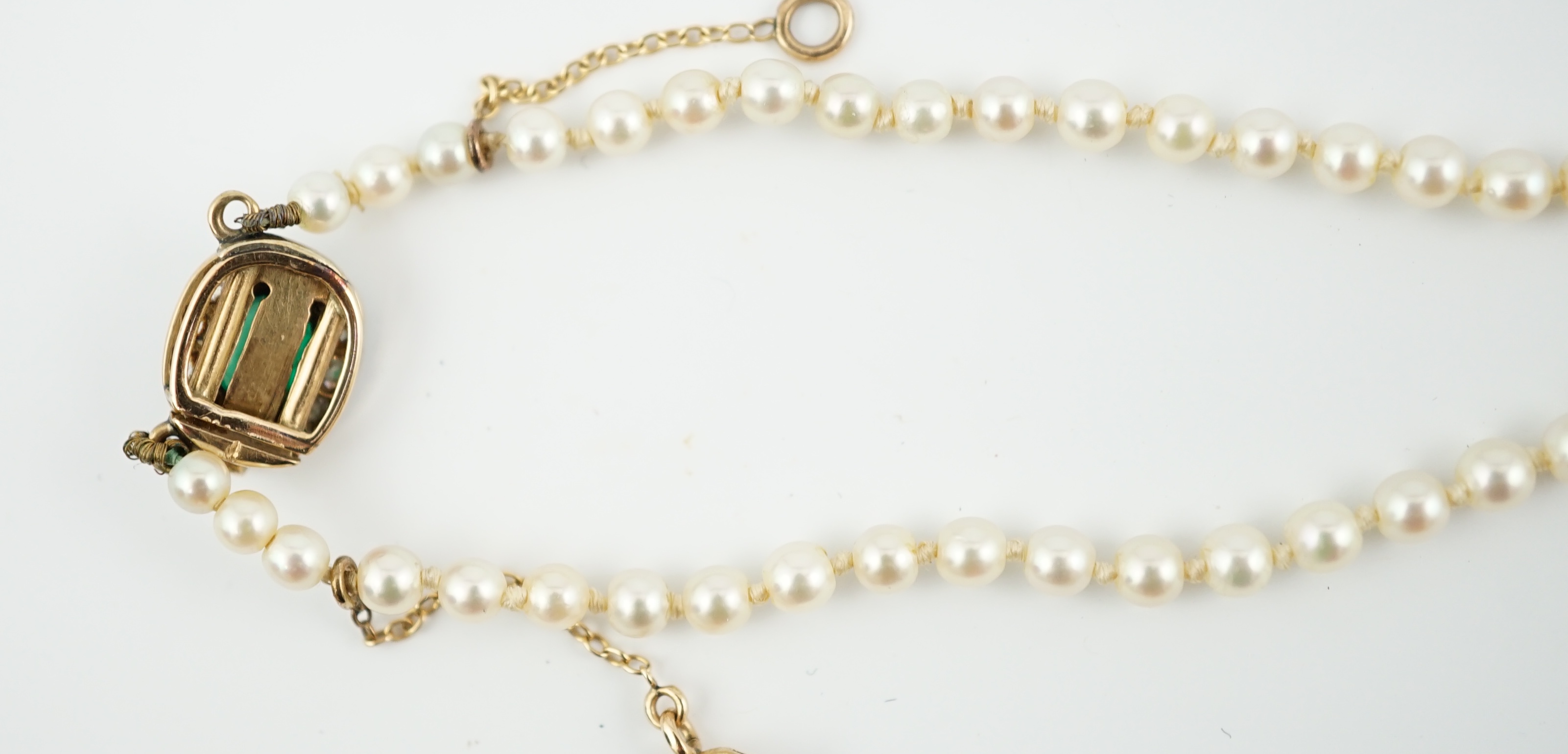 A single strand graduated cultured pearl necklace, with emerald and diamond cluster set gold clasp